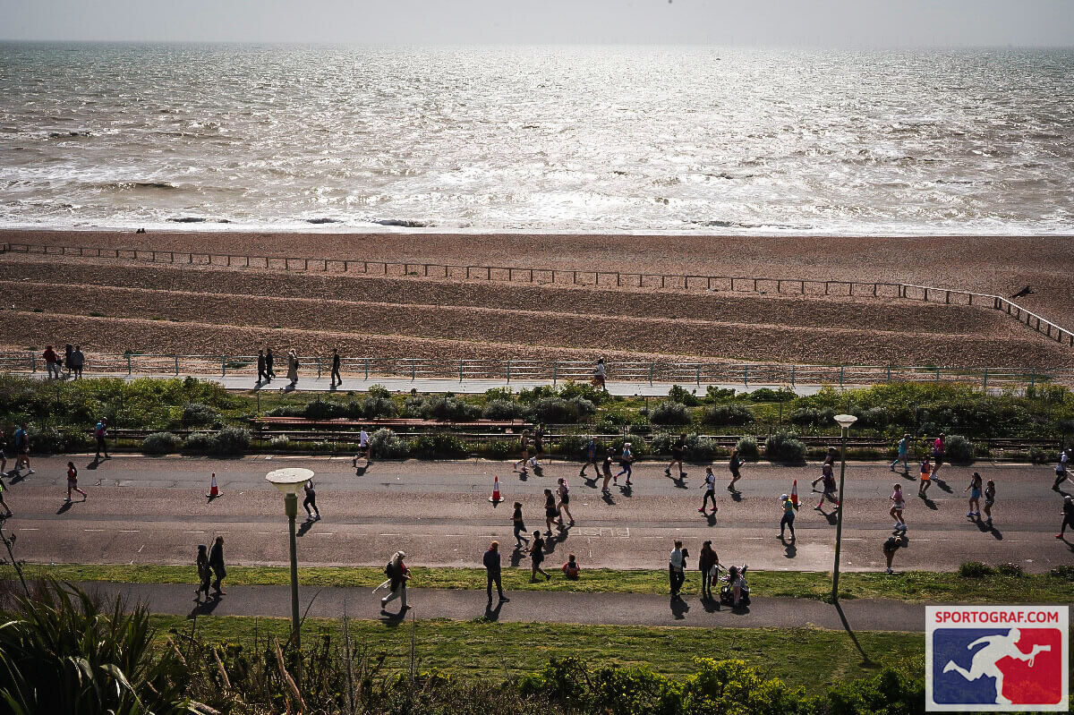 A wide shot of Hove seafront and the beach with runners in the foreground