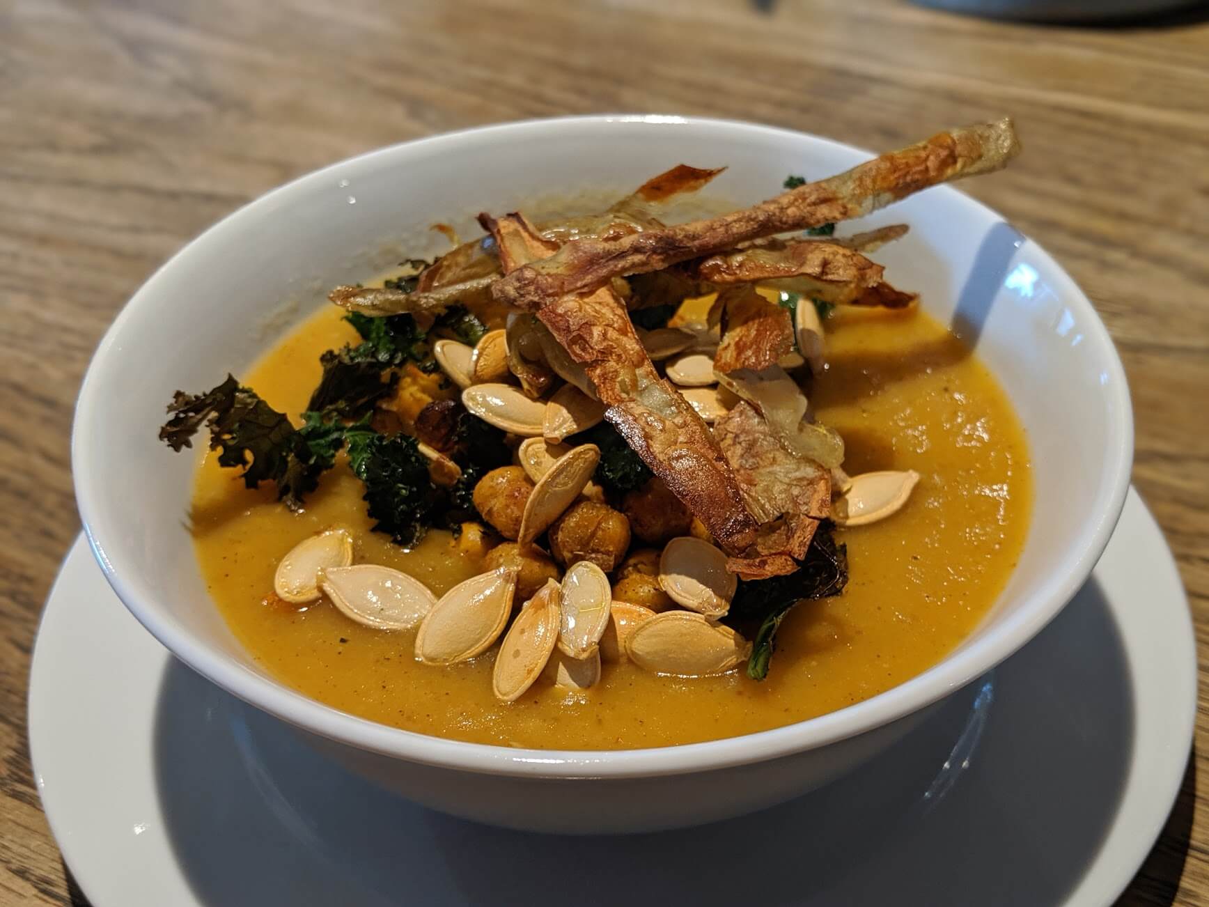 Spiced pumpkin and potato soup, with roasted pumpkin seeds, potato skins, kale and chickpeas