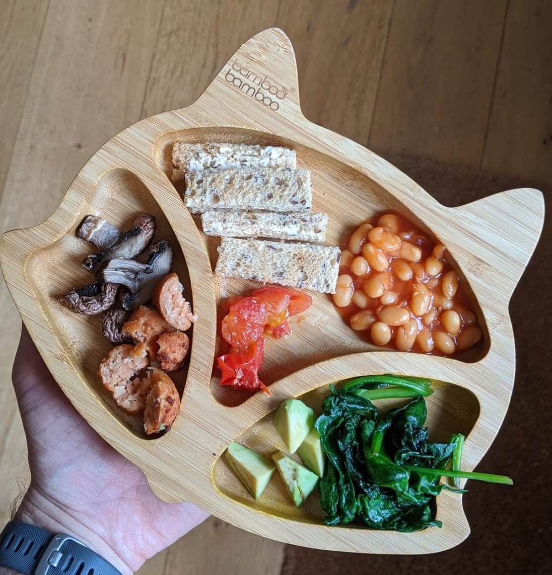 Toast fingers, baked beans, roasted tomatoes, sauted spinach, avocado, fried mushrooms and vegan sausage on Brandon's bamboo plate