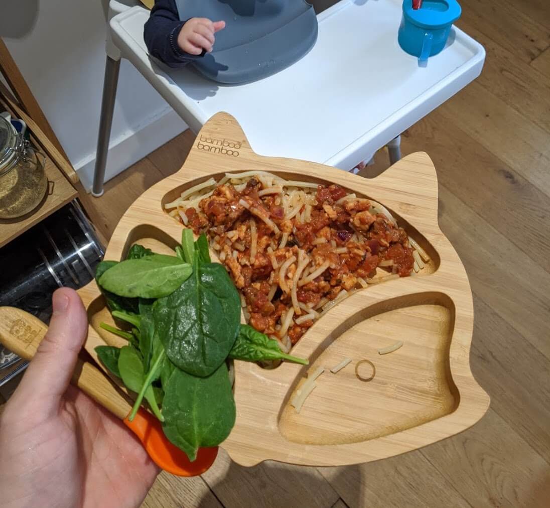 Brandon awaiting his meal of lentil bolognaise with spaghetti and a side of spinach, from his bamboo plate.